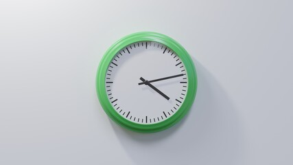 Glossy green clock on a white wall at thirteen past four. Time is 04:13 or 16:13