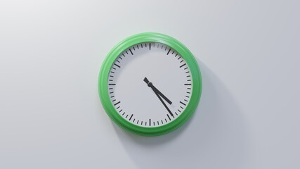 Glossy green clock on a white wall at twenty-four past four. Time is 04:24 or 16:24