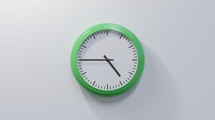 Glossy green clock on a white wall at quarter to five. Time is 04:45 or 16:45