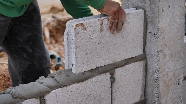 close up at the bricklayer hands, the builder puts the bricks
