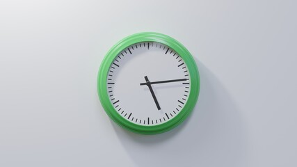 Glossy green clock on a white wall at fourteen past five. Time is 05:14 or 17:14