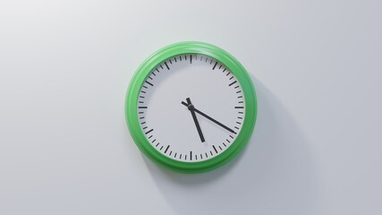 Glossy green clock on a white wall at twenty past five. Time is 05:20 or 17:20