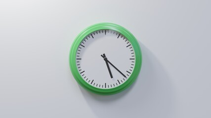 Glossy green clock on a white wall at twenty-two past five. Time is 05:22 or 17:22