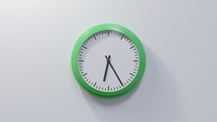 Glossy green clock on a white wall at twenty-five past six. Time is 06:25 or 18:25