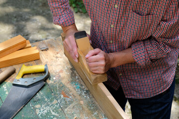 Hand of carpenter woman using planer with wooden plank in carpentry workshop. Woodworking concept.