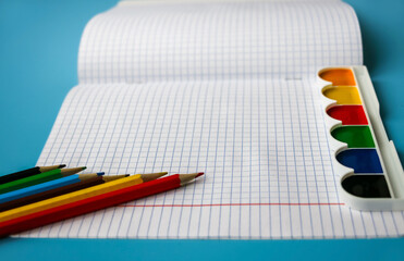 An open notebook in a cage, colored pencils and watercolors on a blue background. Stationery....
