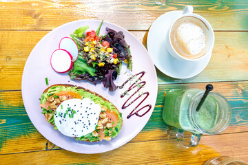 Healthy, fresh and nutritious vegetarian breakfast set-up at the open café - view above. Breakfast is composed of bruschetta with avocado, tomatoes and egg, green smoothie and coffee. 
