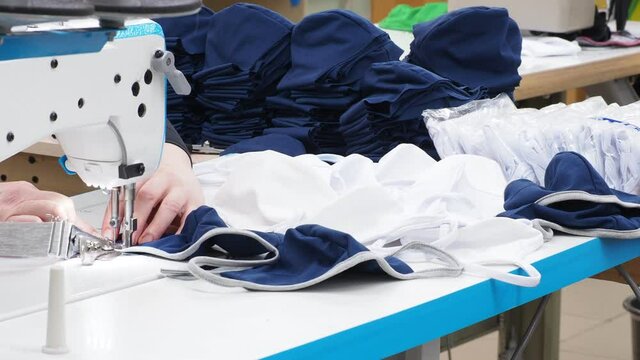 covid-19, close up of sewing process on the overlock in the sewing shop. Tailoring industry. Clothers making atelier with sewing machines. 