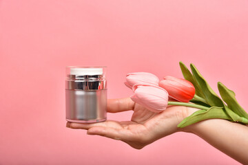 Natural skincare bottle, Hand showing pump cosmetic containers packaging with tulip flower essence extract, Organic beauty product concept.