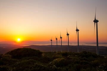 Obraz premium Scenic view of windmill farm at sunset time