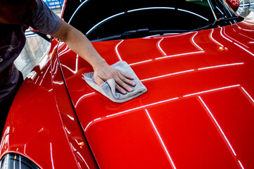 Car service worker polishing car with microfiber cloth.