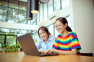 two asian teenager working on laptop computer