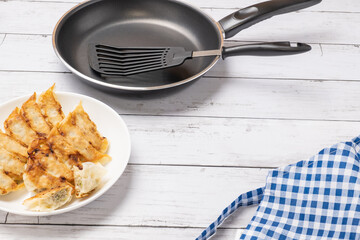 白い木目を背景にしたギョウザを調理したイメージ