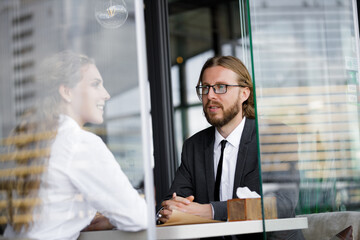 Young businessman in stylish suit talking to a girl in a cafe. Business partners