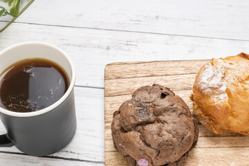 カッティングボードにのせている2種類のシュークリームとコーヒーカップ