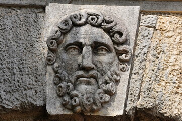 The ancient bas-relief of a male face with a beard.