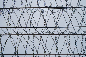 military barbed wire at dusk against cloudy sky