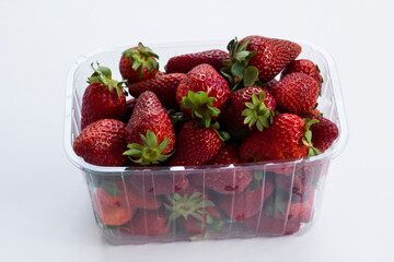 Ripe,fresh delicious strawberries heap in plastic box on white