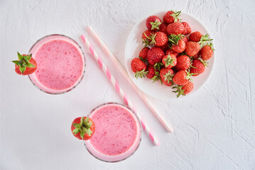 Strawberry milk shake in glass with straw and fresh berries on a white background