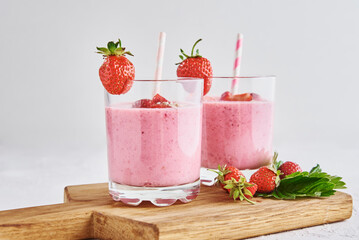 Strawberry milk shake in glass with straw and fresh berries on a white background