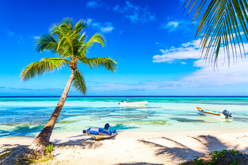 Palm trees on the caribbean tropical beach with boats. Saona Island, Dominican Republic. Vacation travel background