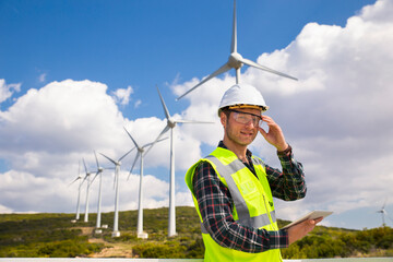 Young worker looking and checking wind turbines at field