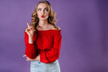 A young beautiful girl shows emotions and smiles in the Studio on a purple background. Girls for advertising