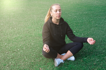 beautiful middle aged woman sitting on a grass in yoga asana. yoga pose lotus. meditation and relaxation concept. inner peace and mindfulness.