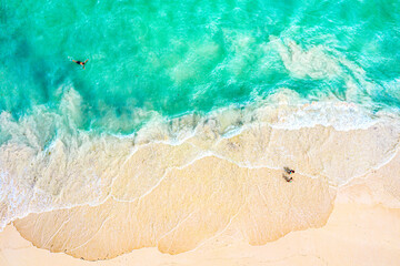 Obraz premium Top view aerial drone photo of ocean seashore with beautiful turquoise water, foam sea waves and people. Caribbean resort. Vacation travel background.