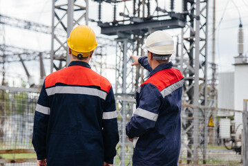 Two specialist electrical substation engineers inspect modern high-voltage equipment. Energy. Industry