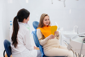 A professional dentist treats and examines the oral cavity of a pregnant girl in a modern dental office. Dentistry