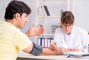 Fototapeta premium Young doctor checking patients blood pressure
