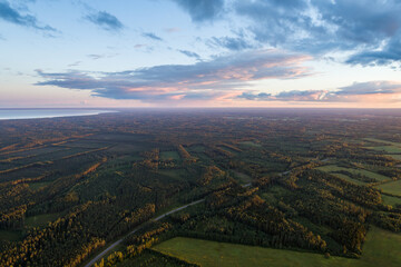 Beautiful sunset over the small town. Fields and trees around. Aerial photography.