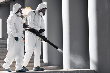 professional cleaning and disinfection at town complex amid the coronavirus epidemic. two workers prevent and control epidemic. in protective suit and mask