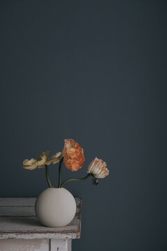 Blumen in einer Vase in gedeckten T&ouml;nen vor dunkler Wand