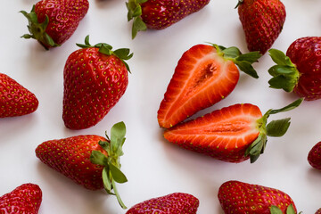 Obraz na płótnie Canvas Fresh,ripe strawberries on white surface,one sliced,flat layout,backgrounds