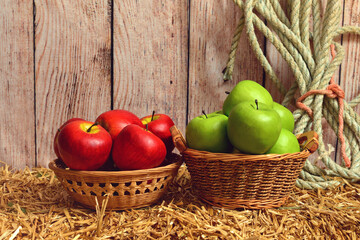 closeup red and green apples in baskets on hay bale
