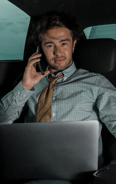 Hombre joven de negocios habla por tel&eacute;fono sentado en el interior de su coche. 
