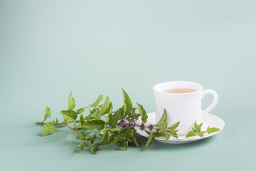 a white Cup of tea with a sprig with mint stands on the table on a gray-green background, morning tea