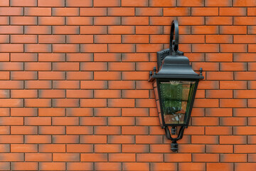 Black Lantern mounted on brown brick wall in exterior. Antique street light