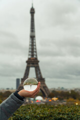 Der Eifelturm wurde durch eine Glaskugel (Lensball) fotografiert. Die Kugel liegt auf einer Hand.