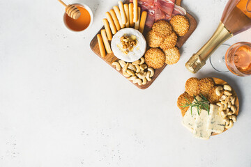 Wooden board with cheese, ham, bread stick, nut cashew, walnut and honey on camembert with glasses of wine on white background