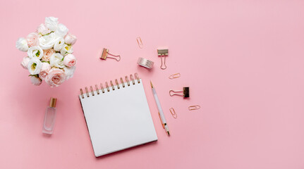 Stationery business flatlay creative composition. Top horizontal view of envelope, spiral blocj paper clips and a pen on abstract pink background.