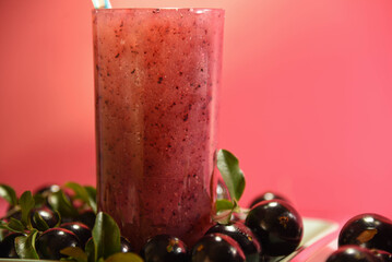 Jabuticaba juice on wooden surface on pink background