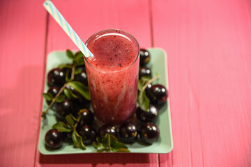 Jabuticaba juice on wooden surface on pink background
