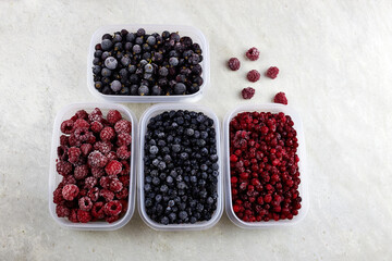 Frozen berries: blueberries, cranberries, raspberries and black currant on a grey background.