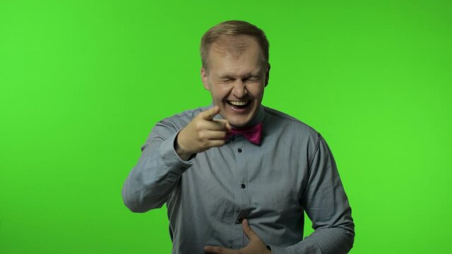 Man pointing finger and laughing out loud, holding belly with hilarious laughter, making fun, joke