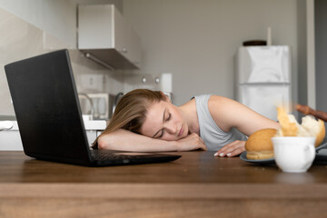 Obraz na płótnie Canvas Tired woman sleeping on table with laptop
