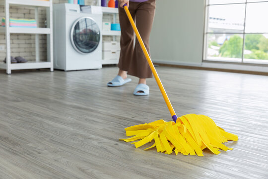 Cropped image of beautiful young woman cleaning floor at home using a yellow mop