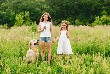 Sisters with dog on flowering meadow